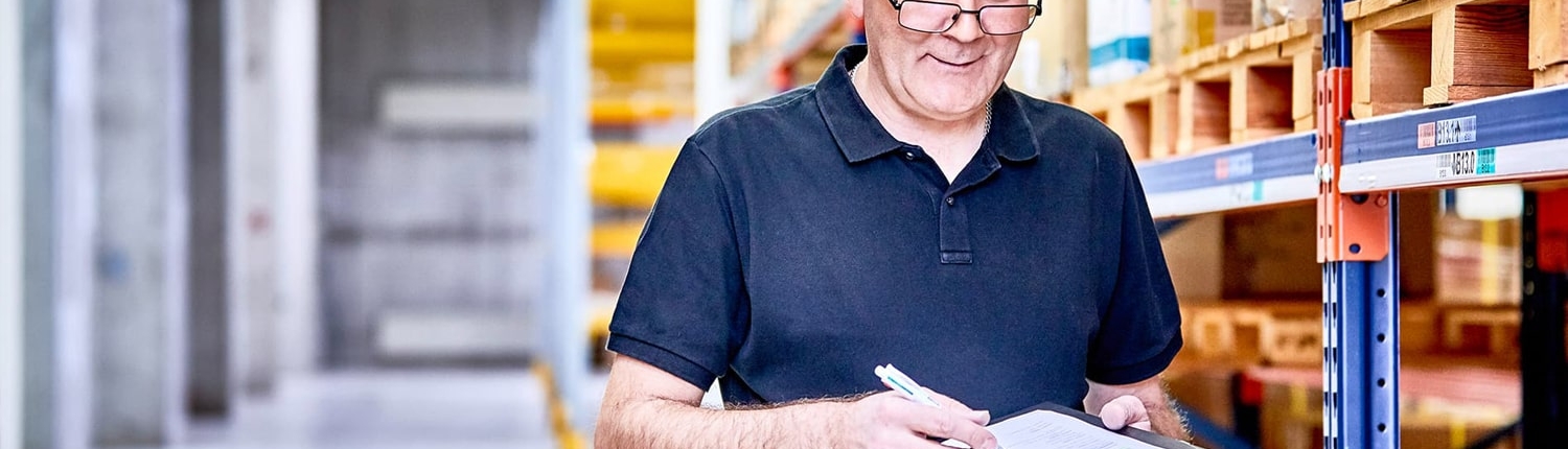 next system Employee with noteboard in the warehouse