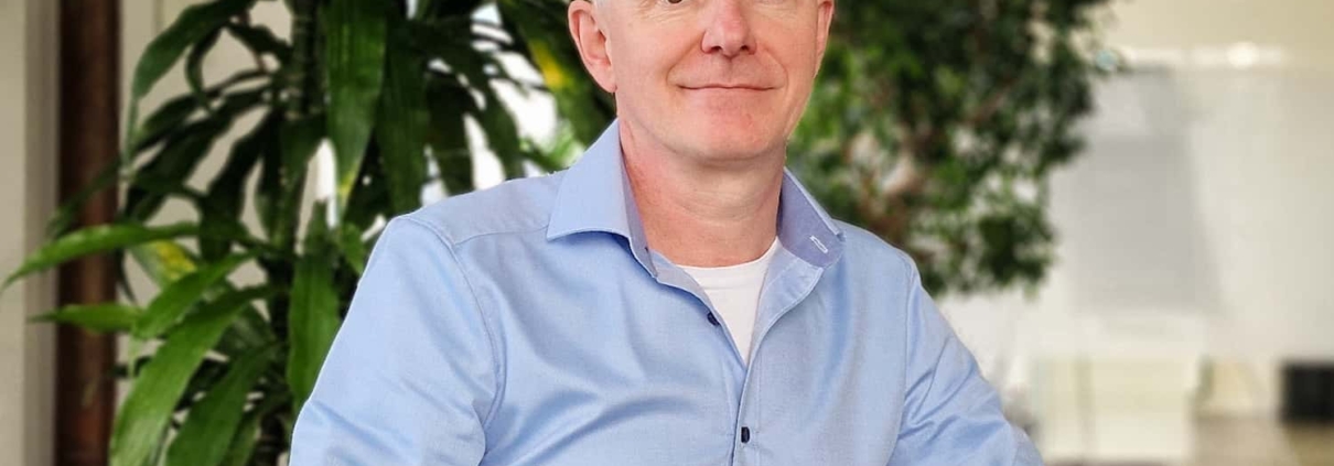 Patrick von Unold, technischer Leiter, auf einem grünen Stuhl vor einer Pflanze sitzend