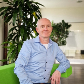 Neuer technischer Leiter bei next system: Patrick von Unold Patrick von Unold, technischer Leiter, auf einem grünen Stuhl vor einer Pflanze sitzend